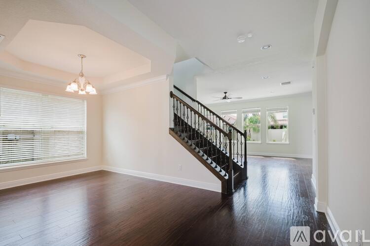 A spacious room with a wooden floor and a staircase.