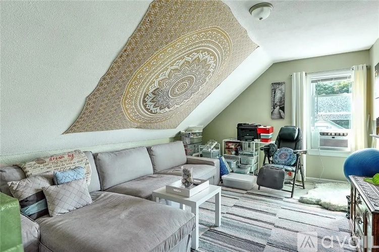 A living room with a grey couch and a patterned ceiling.
