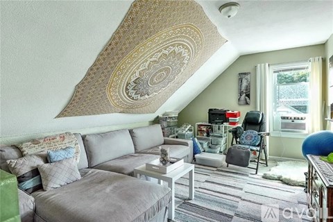 A living room with a grey couch and a patterned ceiling.