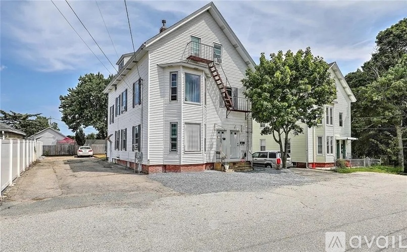 A two-story house with a gravel driveway in front.