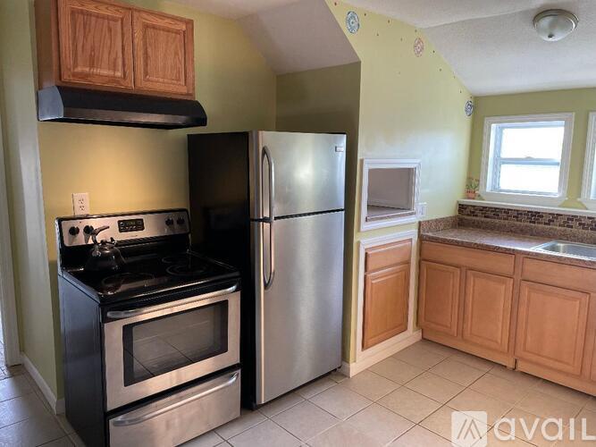 A kitchen with a black stove top oven and a silver refrigerator.
