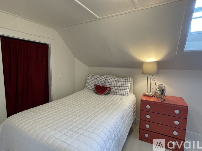 A bedroom with a white bed and a red dresser.