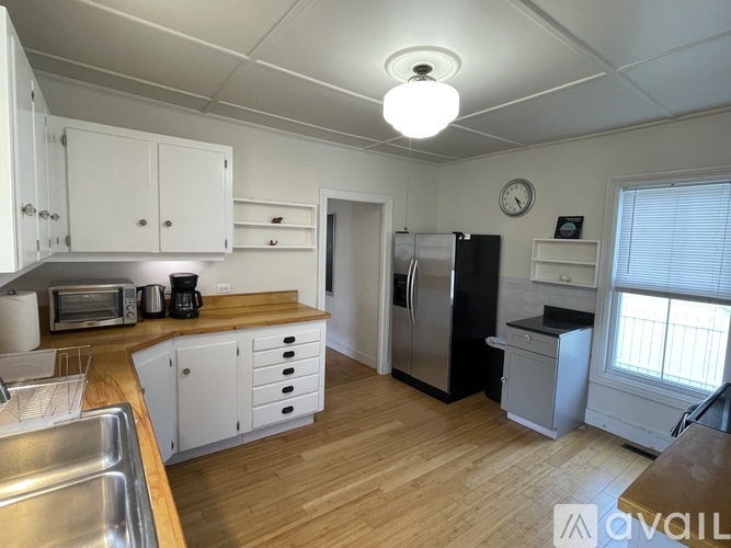 A kitchen with wooden floors and white cabinets.
