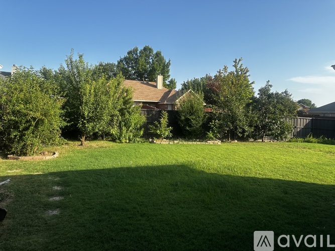 A house with a large lawn and trees in the background.