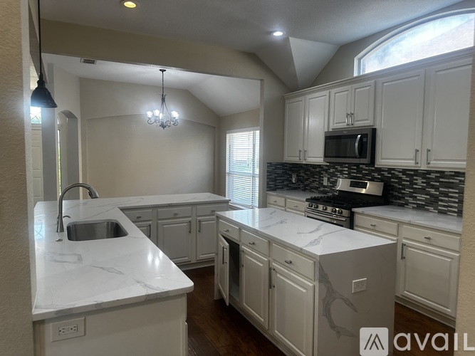 A kitchen with white cabinets and a marble countertop.