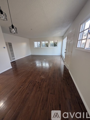 A room with wooden flooring and white walls.