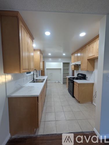 A kitchen with wooden cabinets and white countertops is available for rent.
