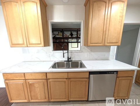 A kitchen with wooden cabinets and white countertops is available for rent.