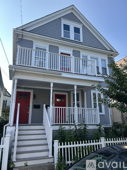 A two-story house with a red door and white railings.