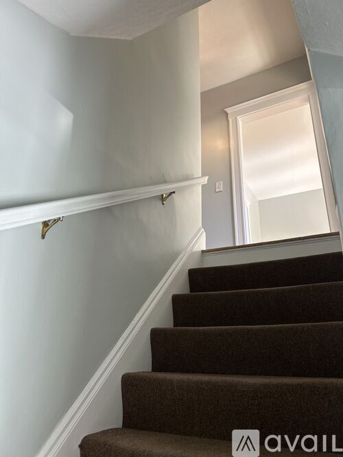A staircase with a brown carpeted runner and white walls.