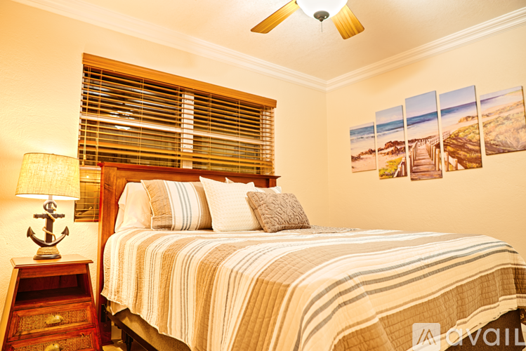 A bedroom with a bed, a lamp, and pictures on the wall.