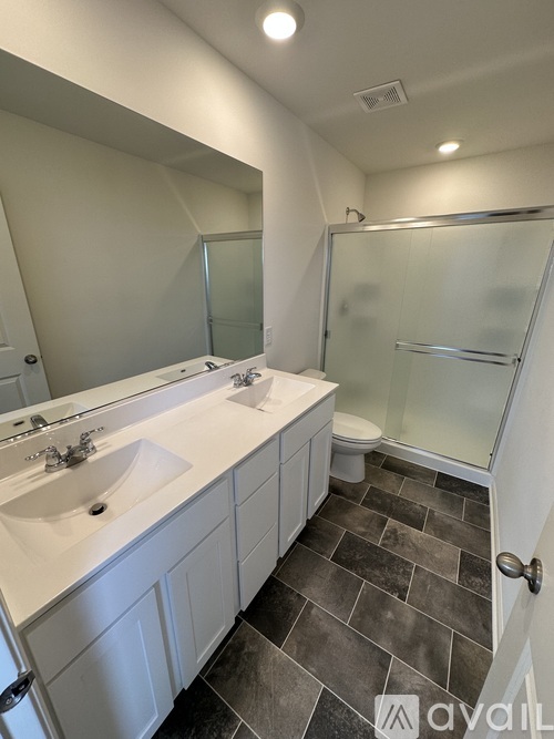 A bathroom with a walk-in shower and double sinks.