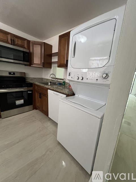 A white dishwasher is in a kitchen with wooden cabinets.