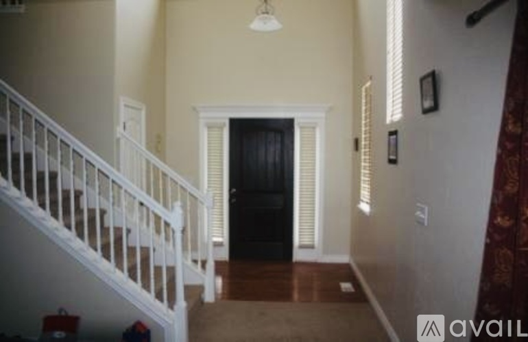 A hallway with a black door and a white staircase.