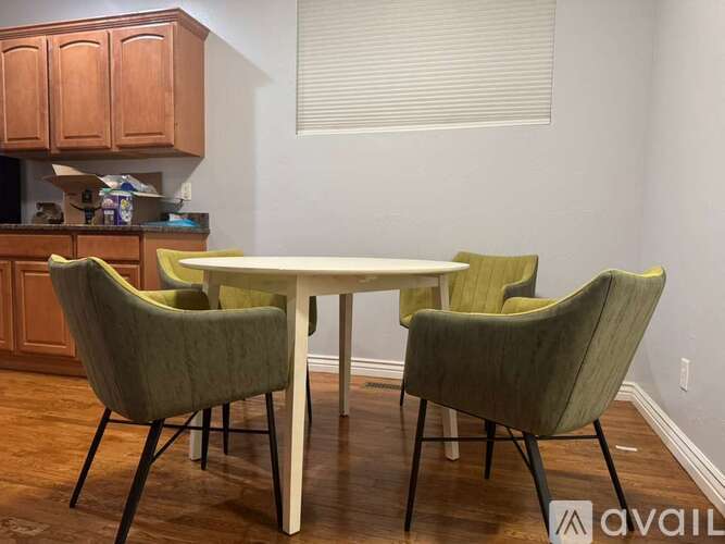 A dining room with a white table and green chairs.