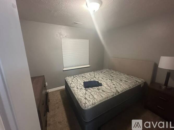 A bedroom with a bed, nightstand, and lamp.