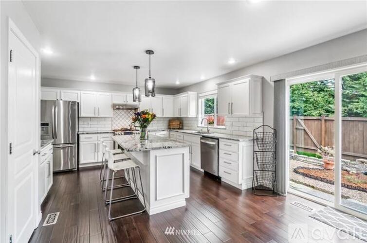 A kitchen with white cabinets and a marble island.