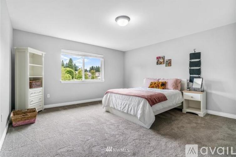 A bedroom with a large bed and a window showing trees outside.