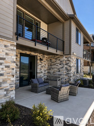 A patio with a couch, chairs, and a table is in front of a house.