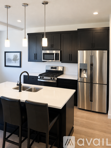 A modern kitchen with a stainless steel refrigerator and black cabinets.