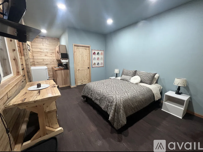 A bedroom with a bed, nightstand, and a wooden desk.