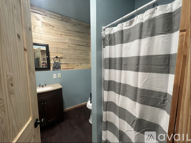 A bathroom with a striped shower curtain and wooden walls.