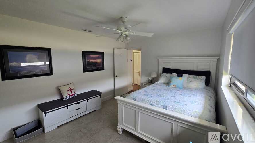 A bedroom with a bed, dresser, and two framed pictures on the wall.