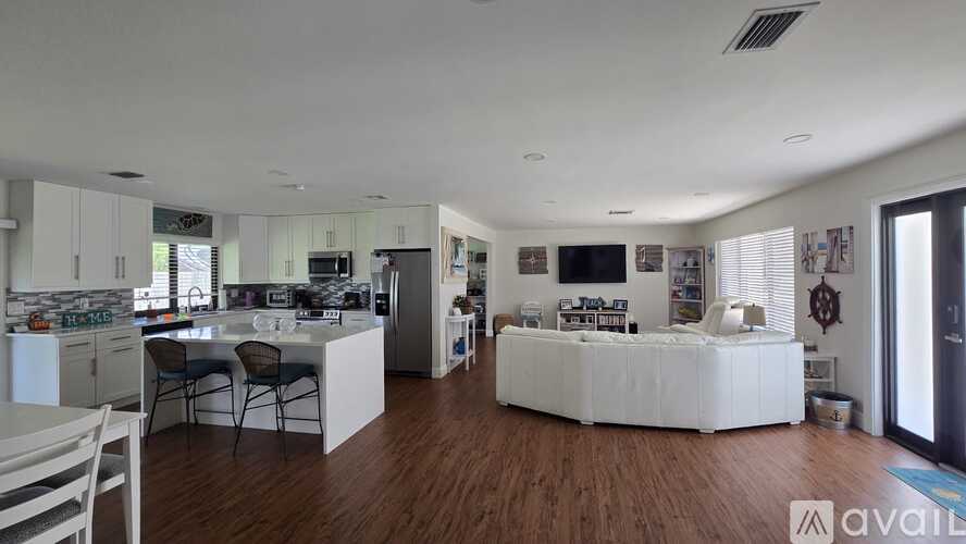 A spacious open plan living and kitchen area with white furniture.