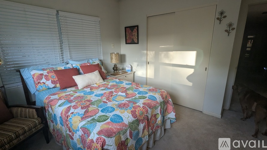 A bedroom with a bed covered in a floral print bedspread and a striped chair.