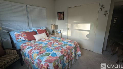A bedroom with a bed covered in a floral print bedspread and a striped chair.