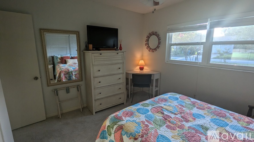 A bedroom with a bed, dresser, and mirror.