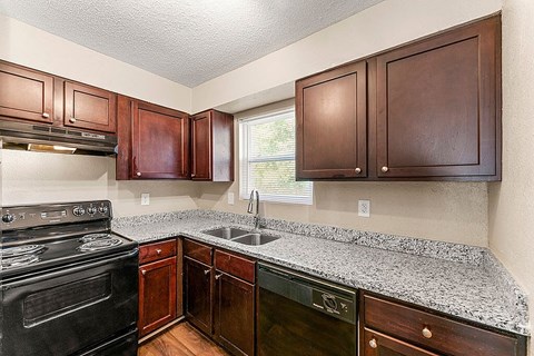 A kitchen with a black stove top oven and wooden cabinets.