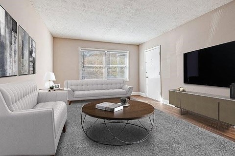 A living room with a white couch, a coffee table, and a television.