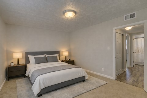 A bedroom with a large bed and two lamps on either side of it.