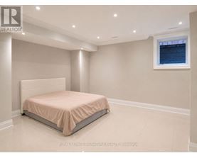 A bedroom with a bed, a window, and recessed lighting.
