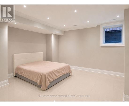 A bedroom with a bed, a window, and recessed lighting.