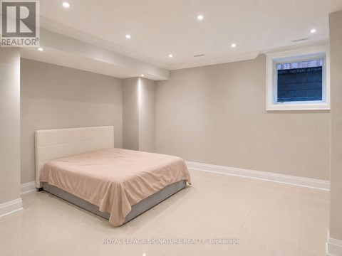 A bedroom with a bed, a window, and recessed lighting.