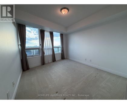 A spacious room with a large window and carpeted floor.