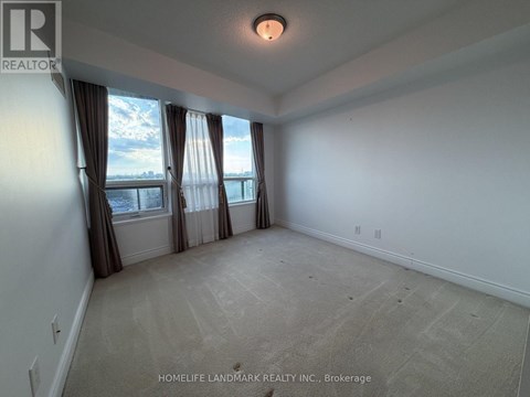 A spacious room with a large window and carpeted floor.