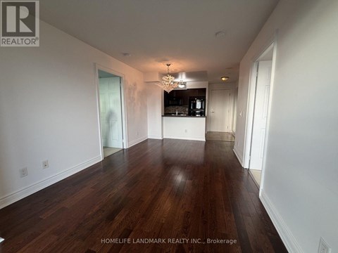A spacious room with wooden floors and a chandelier.