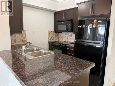 A kitchen with granite countertops and black appliances.