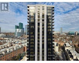 A tall building with a glass facade stands in the foreground of a cityscape.