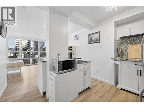 A kitchen with white cabinets and a large window overlooking the city.