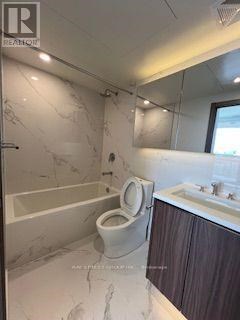 A white toilet in a bathroom with marble flooring and walls.