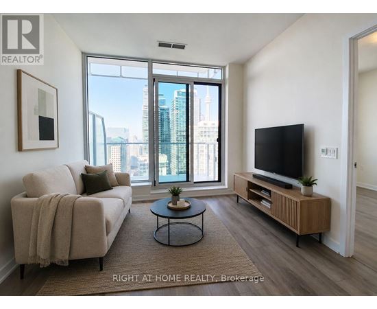 A living room with a couch, a coffee table, and a television.