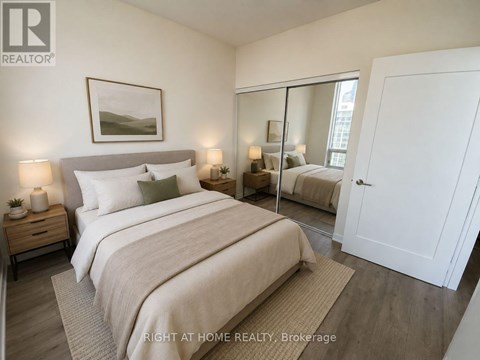 A bedroom with a large bed, a mirror, and a nightstand with a lamp.
