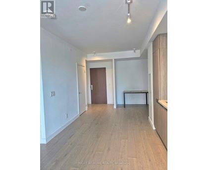A spacious room with wooden flooring and white walls.