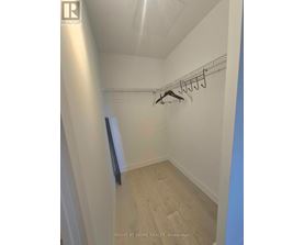 A hallway with a coat rack and a door on the left.