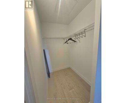 A hallway with a coat rack and a door on the left.