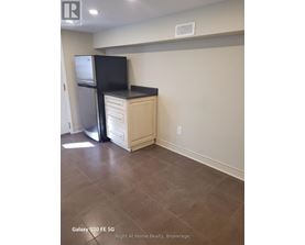 A kitchen area with a black fridge and a black flat screen TV on a cabinet.